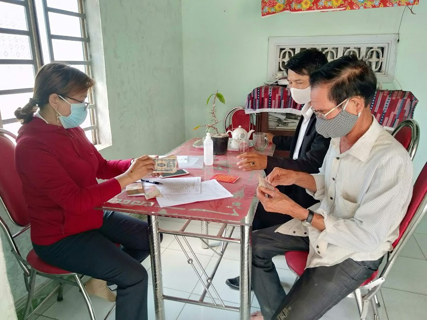 Nhân viên Bưu điện huyện Thăng Bình chi trả trợ cấp thương binh cho gia đình ông Trương Thanh Sơn ở xã Bình Phục.Ảnh: T.T