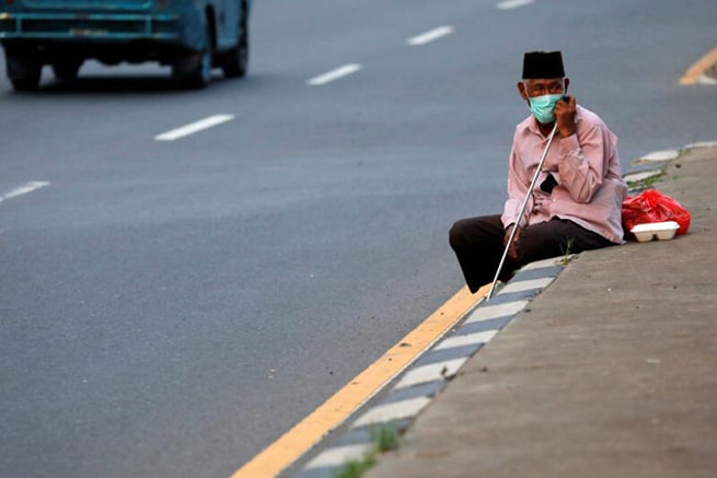 Một người lao động Indonesia ngồi bên lề đường khi đang tìm cách trở về quê. Ảnh: Straits Times