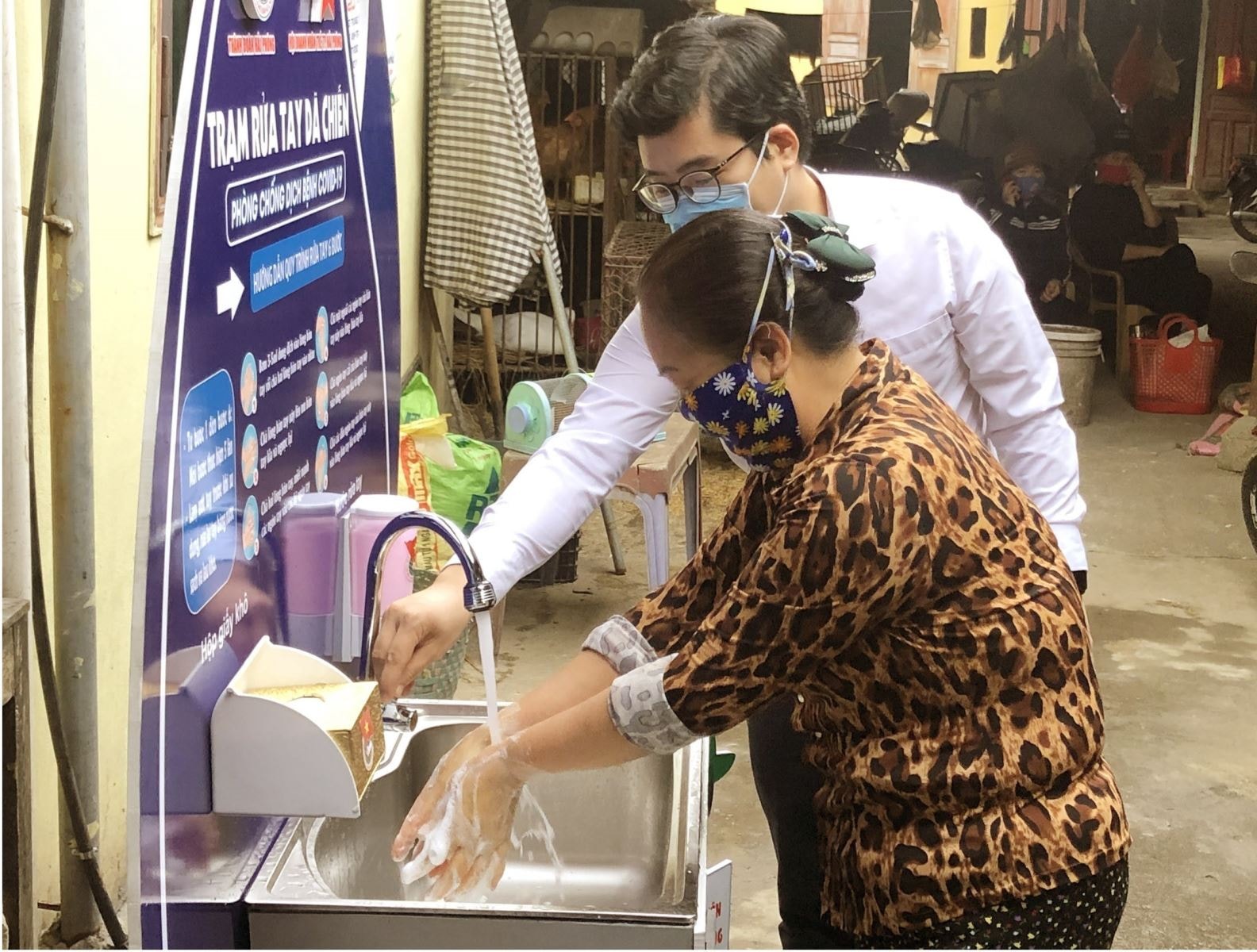 Hướng dẫn người dân rửa tay tại trạm rửa tay dã chiến. Ảnh: TTXVN
