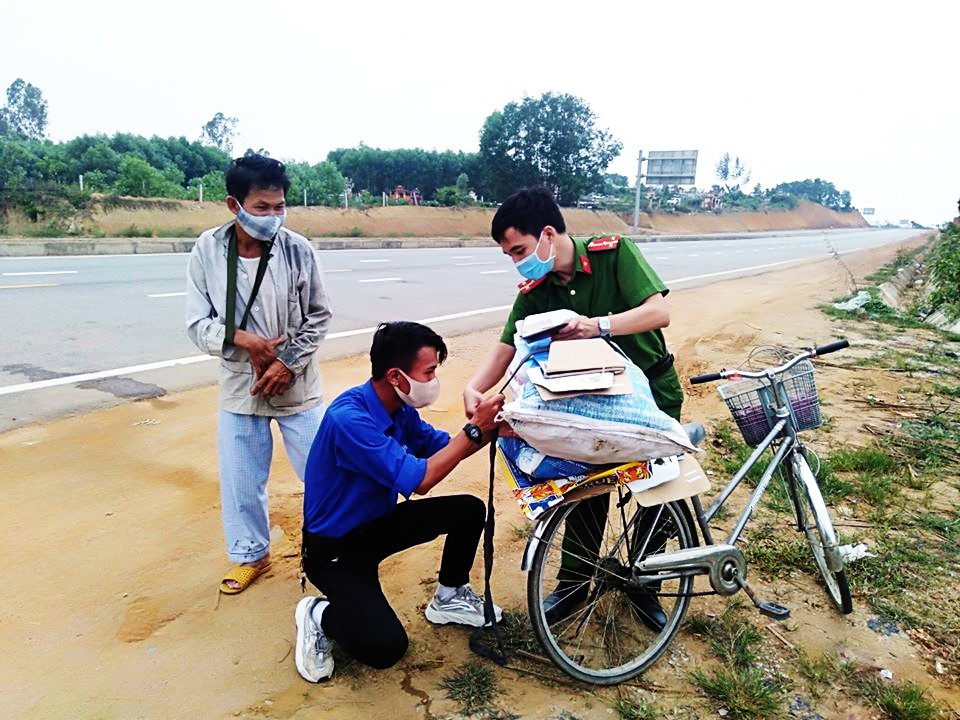 Bạn  Nguyễn Triệu Vĩ và chiễn sĩ công an hỗ trợ người dân khi đi qua chốt kiểm soát lên cao tốc Quảng Ngãi – Đà Nẵng. Ảnh: THÁI CƯỜNG