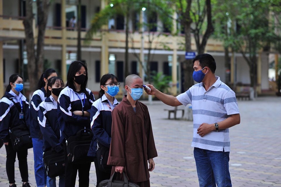 Đo thân nhiệt cho học sinh trước khi vào trường. Ảnh: Vũ Vân.