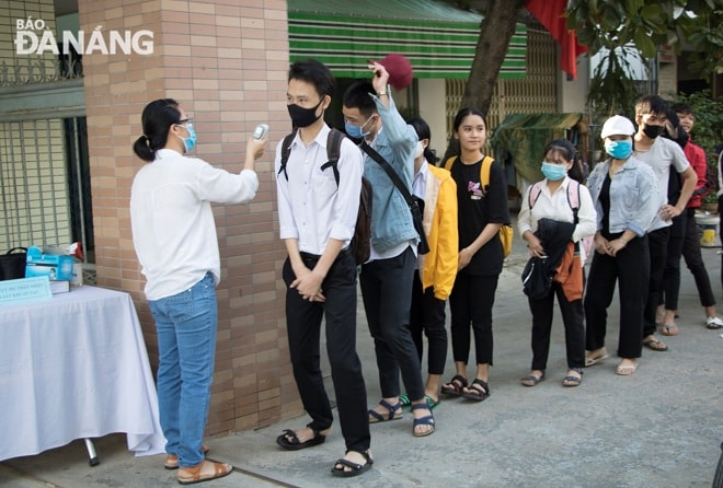 Ngay tại cổng trường, cán bộ y tế tiến hành đo thân nhiệt để bảo đảm sức khỏe cho sinh viên. Ảnh: VĂN HOÀNG
