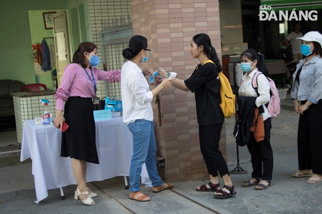 Mỗi sinh viên được cán bộ y tế nhắc nhở việc mang khẩu trang. Trong sáng 4-5, nhiều sinh viên chưa mang khẩu trang được nhà trường phát miễn phí để phòng tránh dịch bệnh. Ảnh: VĂN HOÀNG