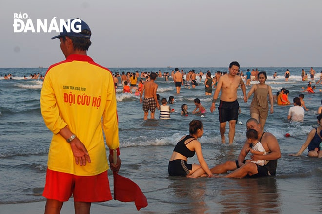 Lực lượng cứu hộ luôn nâng cao cảnh giác nhắc nhở người dân tắm biển an toàn. Theo ghi nhận, tại mỗi khu vực cho phép tắm biển luôn có từ 2-3 nhân viên cứu hộ, người cầm còi, cờ hướng dẫn người dân không tắm tại khu vực nguy hiểm, người trèo thuyền thúng ra khu vực nước sâu để để có mặt kịp thời, bảo đảm không xảy ra trường hợp đuối nước. Ảnh XUÂN DŨNG