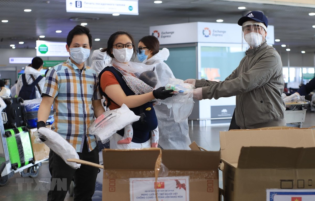 Đại diện Đại sứ quán Việt Nam trao tặng đồ bảo vệ cá nhân cho công dân chuẩn bị lên máy bay về nước. (Ảnh: Trần Hiếu/TTXVN)