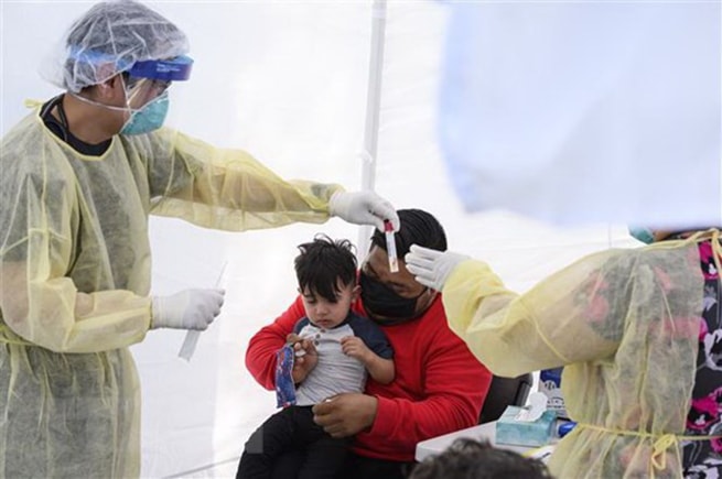 Lấy mẫu dịch xét nghiệm Covid-19 cho trẻ nhỏ. (Ảnh: AFP/TTXVN)