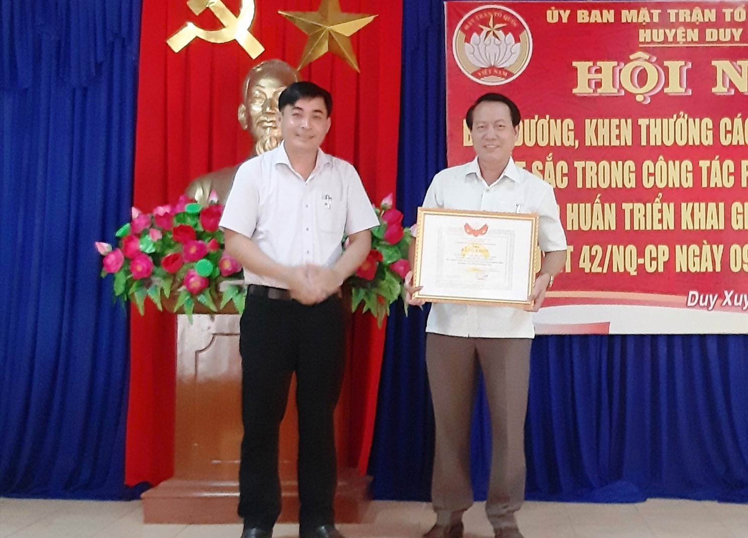 Lãnh đạo Ủy ban MTTQ Việt Nam huyện Duy Xuyên trao bằng khen của Mặt trận tỉnh cho đại diện Mặt trận xã Duy Trinh. Ảnh: HOÀI NHI