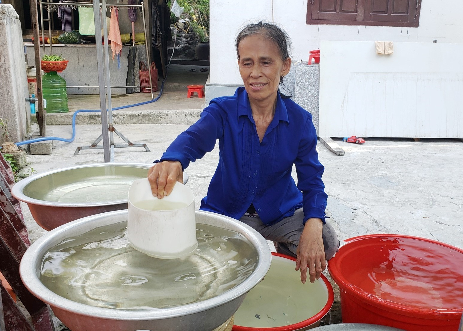 Bà Trần Thị Lịa dùng các vật dụng trữ nước lại để sinh hoạt. Ảnh: THANH THẮNG