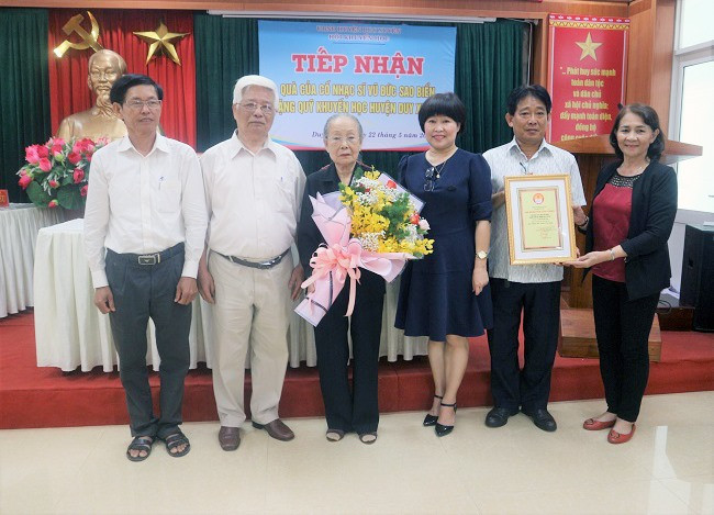 Lãnh đạo huyện Duy Xuyên tặng hoa và bản ghi nhận cho gia đình cố nhạc sĩ.