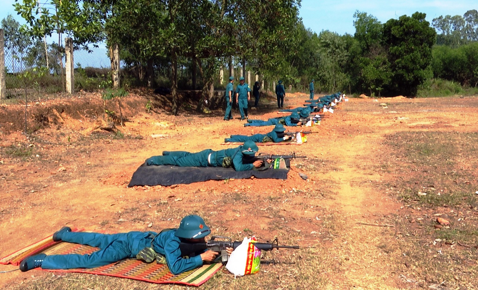 Các chiến sĩ dân quân thực hiện huấn luyện bài bắn súng trên thao trường.