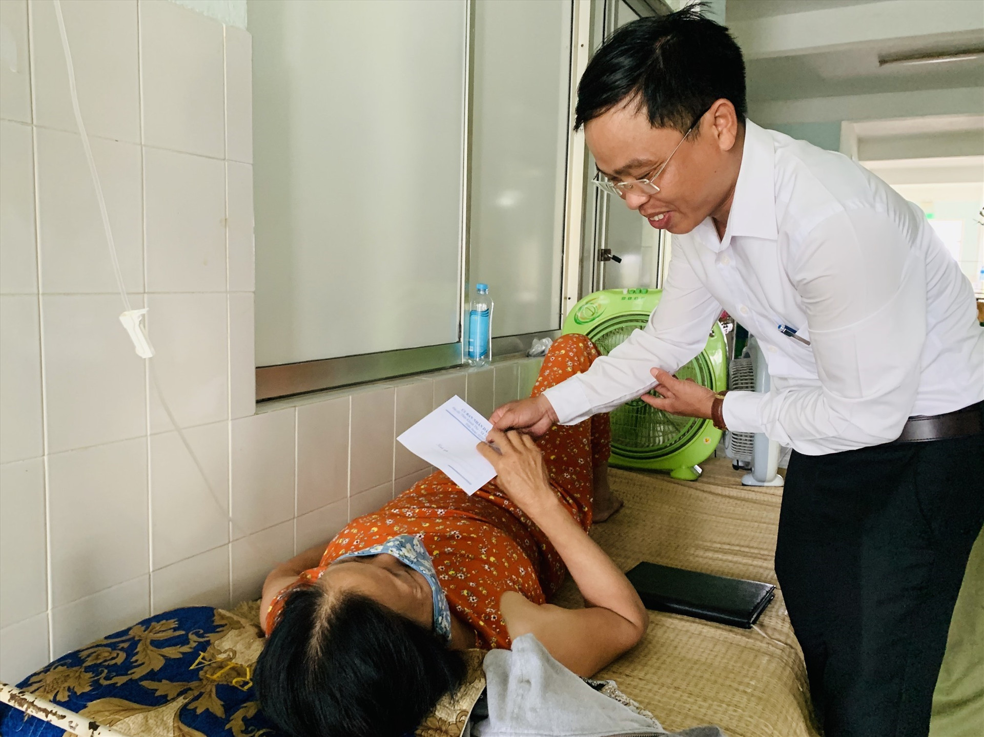 Ông Phan Văn Phẩm - Chủ tịch UBND xã Tam Thái thăm hỏi, động viên sức khỏe người dân đang nằm viện. Ảnh: PHAN VINH