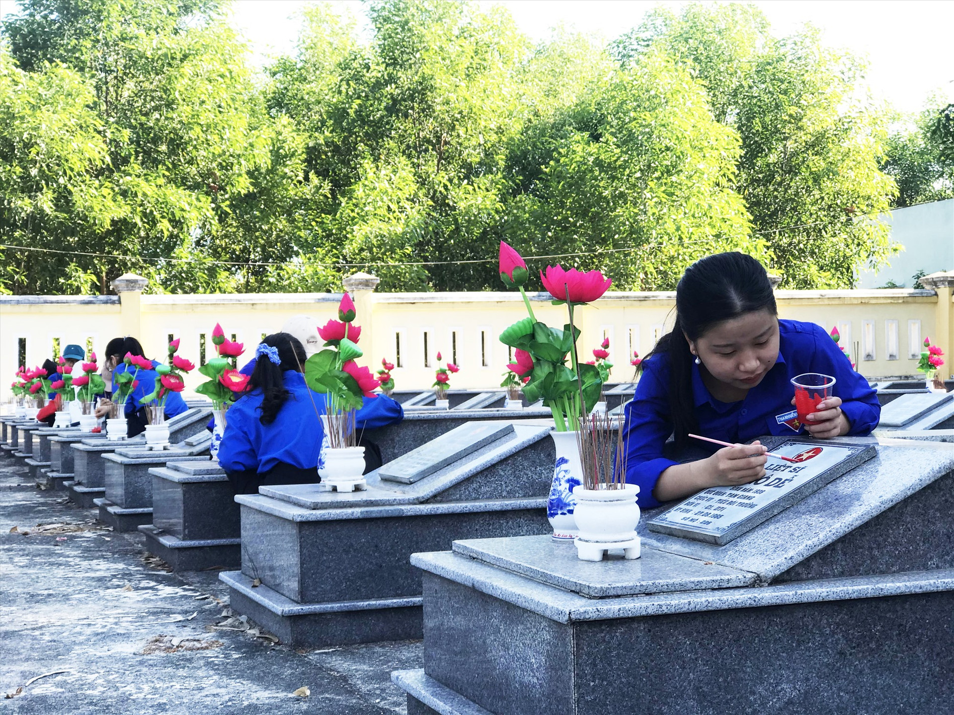 Sơn lại biểu tượng cờ Tổ quốc trên phần mộ tại Nghĩa trang liệt sĩ xã Tam Giang (Núi Thành). Ảnh: THÁI CƯỜNG