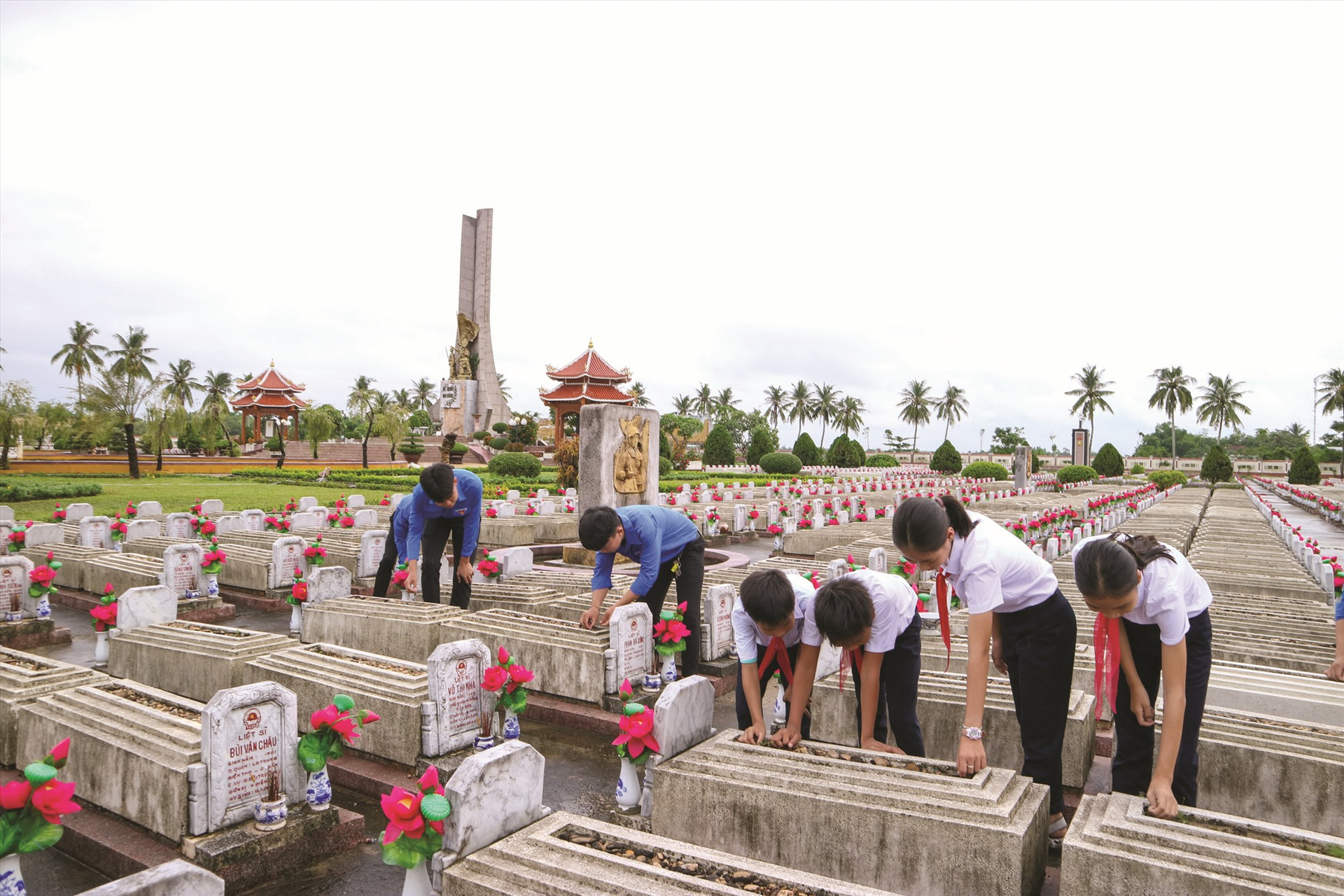 Học sinh tham gia chăm sóc phần mộ liệt sĩ ở Nghĩa trang liệt sĩ Điện Bàn. Ảnh: PHƯƠNG THẢO