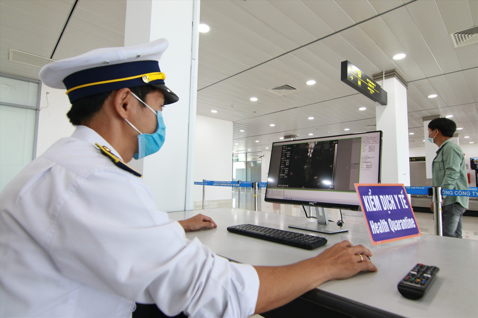 Nhân viên kiểm tra thân nhiệt hành khách bằng máy quét thân nhiệt tự động lắp đặt ở khu vực an ninh sân bay Chu Lai. Ảnh: T.C