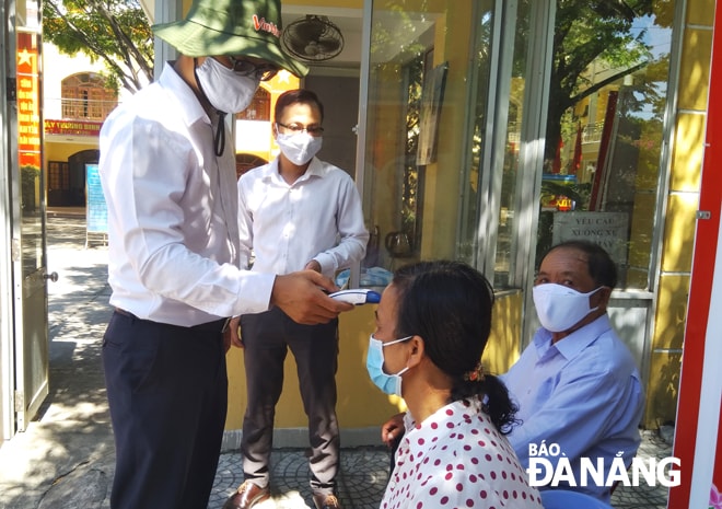 Công dân, tổ chức đến liên hệ giải quyết hồ sơ về thế chấp ngân hàng và nhận chuyển nhượng đất đai được cán bộ, chuyên viên đón tiếp, hướng dẫn ngay từ ngoài cổng trụ sở UBND các quận, huyện trong thời gian giãn cách xã hội. TRONG ẢNH: Đơn vị chức năng đo thân nhiệt cho công dân trước khi hướng dẫn, liên hệ làm thủ tục hành chính tại quận Sơn Trà.  Ảnh: HOÀNG HIỆP