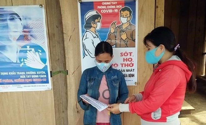 Members of a monitoring group and a poster for Covid-19 prevention and control