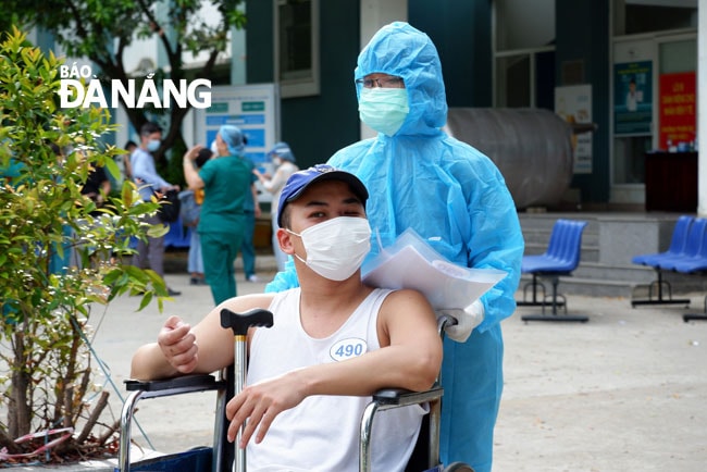 Nhân viên y tế hỗ trợ đưa bệnh nhân được điều trị khỏi ra xe. Ảnh: PHAN CHUNG
