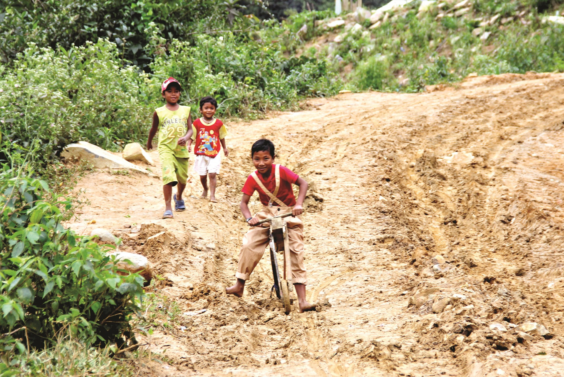 Những đứa trẻ vùng cao dùng chiếc xe gỗ tự chế để chơi. Trên con đường đầy bùn đất, bánh xe trượt lăn theo tiếng cười thỏa thích.