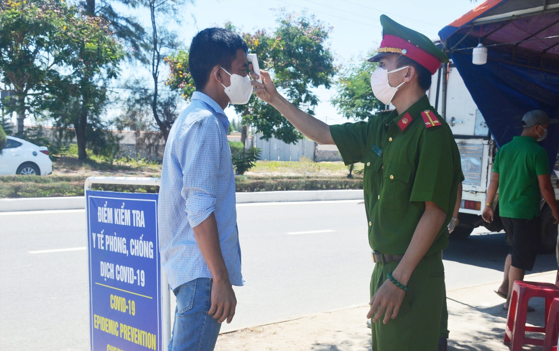 Kiểm soát thân nhiệt người dân tại một chốt chặn ở thị xã Điện Bàn. Ảnh: Q.T