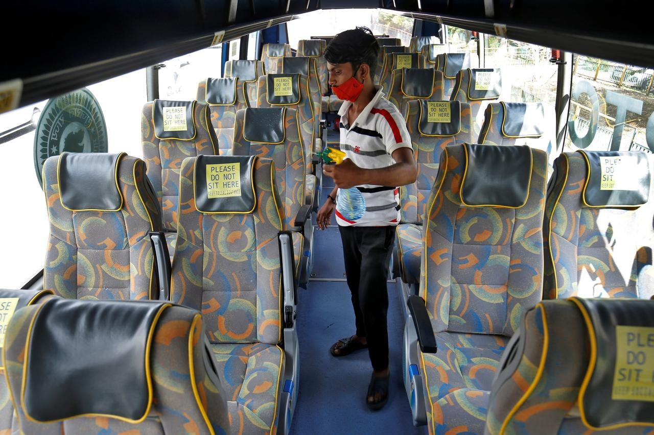 Một nhân viên khử trùng ghế ngồi của xe buýt chở khách tại Ấn Độ sau khi nhà chức trách bang Gujarat nối lại dịch vụ xe buýt sau khi nới lỏng giãn cách xã hội. Ảnh: Reuters