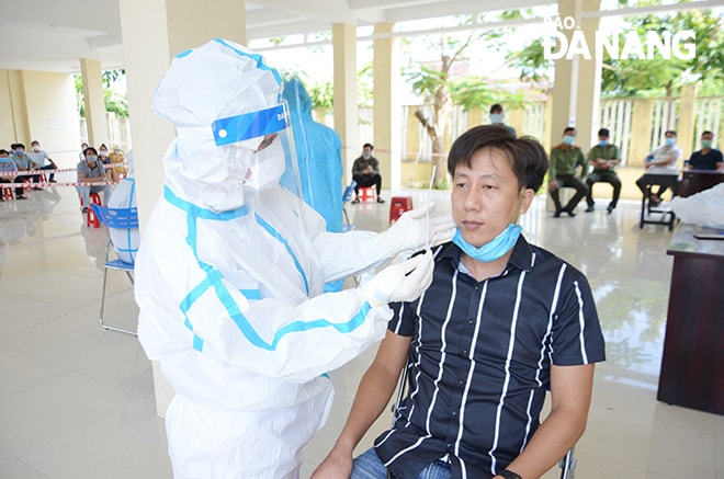 Nhân viên y tế lấy mẫu xét nghiệm cho cán bộ giáo viên coi thi tại điểm thi Trường THPT Võ Chí Công. Ảnh: NGỌC PHÚ