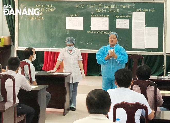 Cán bộ y tế hướng dẫn cán bộ, giáo viên mang bảo hộ khi tham gia coi thi. Ảnh: NGỌC PHÚ