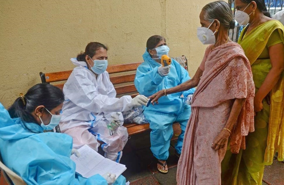 Nhân viên y tế đo nồng độ ô xy và kiểm tra nhiệt độ người dân tại Mumbai, Ấn Độ. Ảnh: AFP
