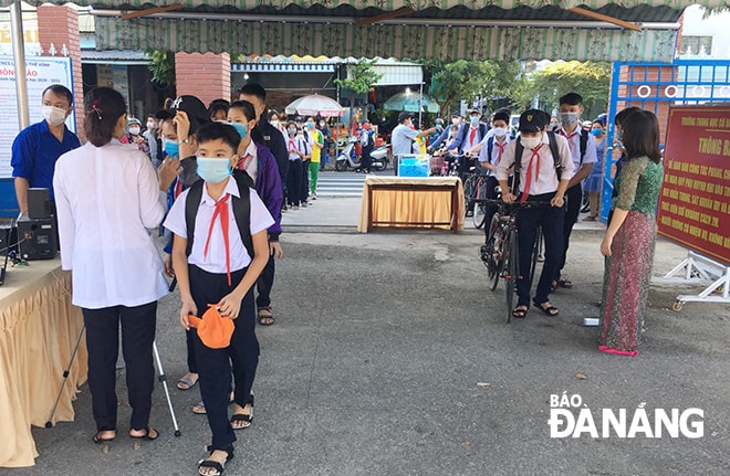 Trường THCS Lương Thế Vinh (quận Liên Chiểu) phân luồng học sinh đi theo 2 hàng trước khi vào lớp. Các em được đo thân nhiệt, sát khuẩn tay, mang khẩu trang phòng, chống Covid-19.