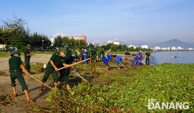 Cán bộ, chiến sĩ Đồn Biên Phòng Phú Lộc và đoàn viên, công nhân Công ty CP Môi trường Đô thị Đà Nẵng thu gom rác tấp vào bờ biển dọc đường Nguuyễn Tất Thành. Ảnh: HOÀNG HIỆP