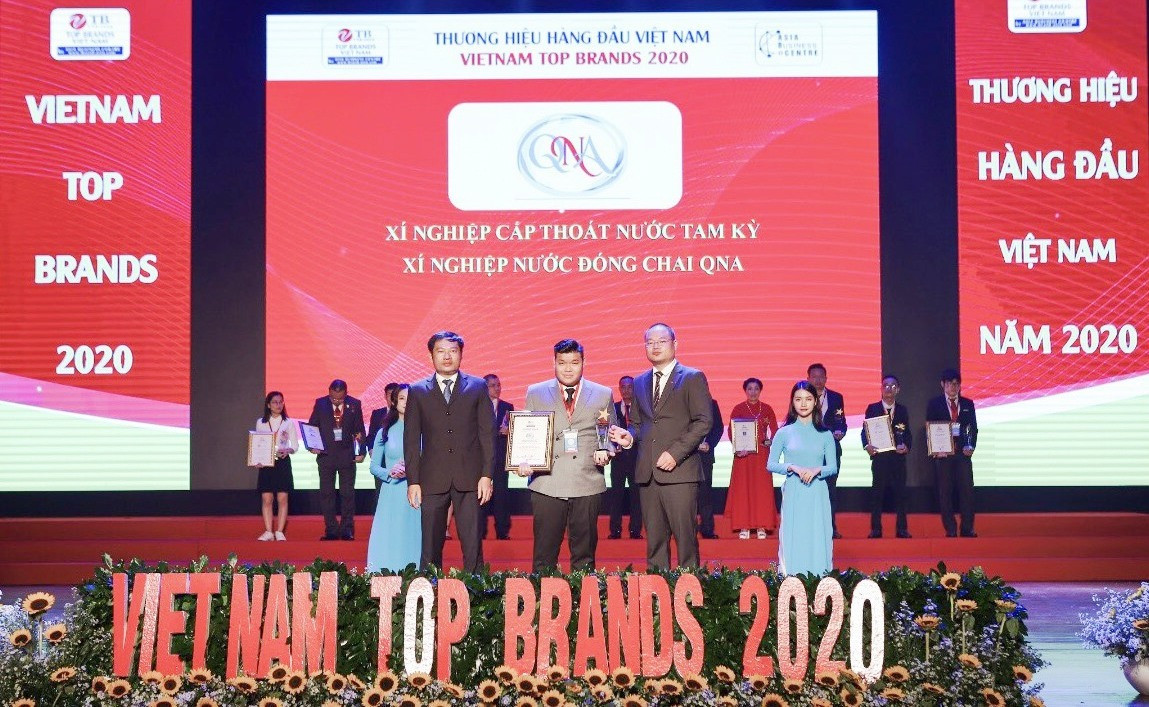 Giám đốc Xí nghiệp nước uống đóng chai QNA Ngô Trần Đức Tín nhận chứng nhận và cup vinh danh đạt “Top 50 thương hiệu hàng đầu Việt Nam năm 2020”. Ảnh: L.D
