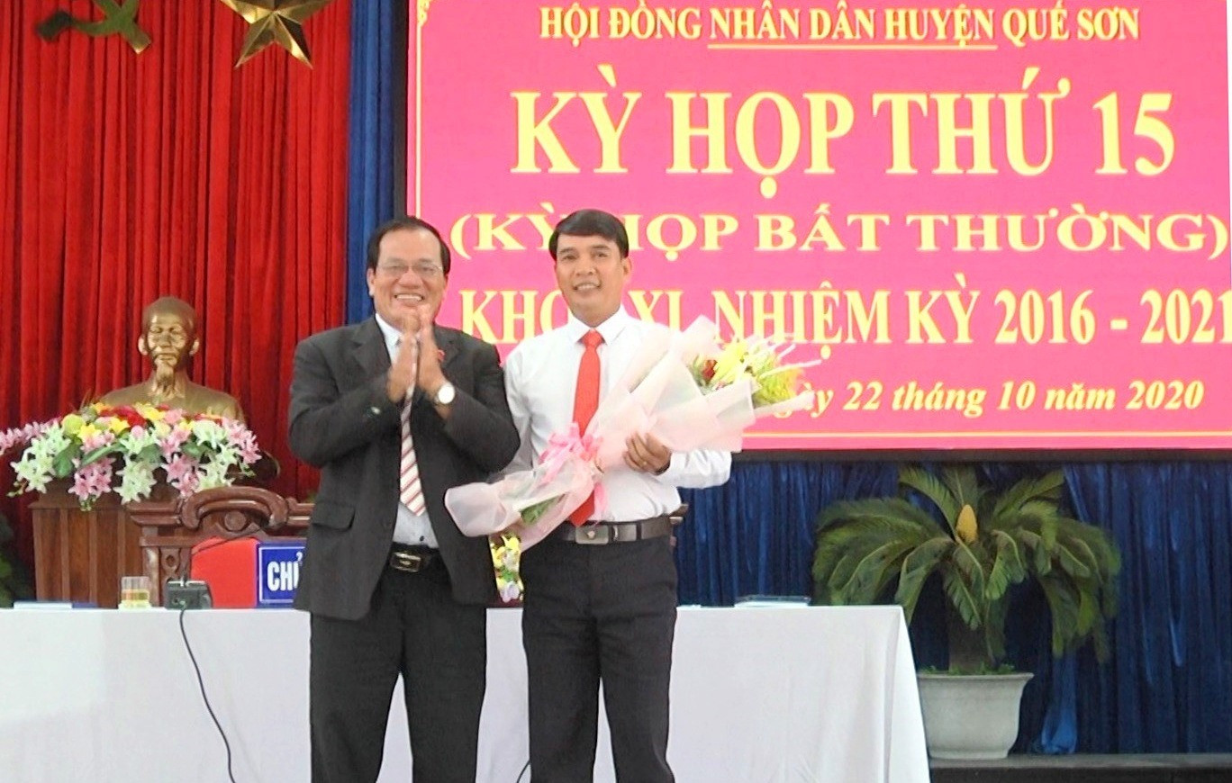 Ông Lê Tấn Trung - Chủ tịch HĐND huyện Quế Sơn (bên trái) tặng hoa chúc mừng ông Nguyễn Minh Châu. Ảnh: T.S