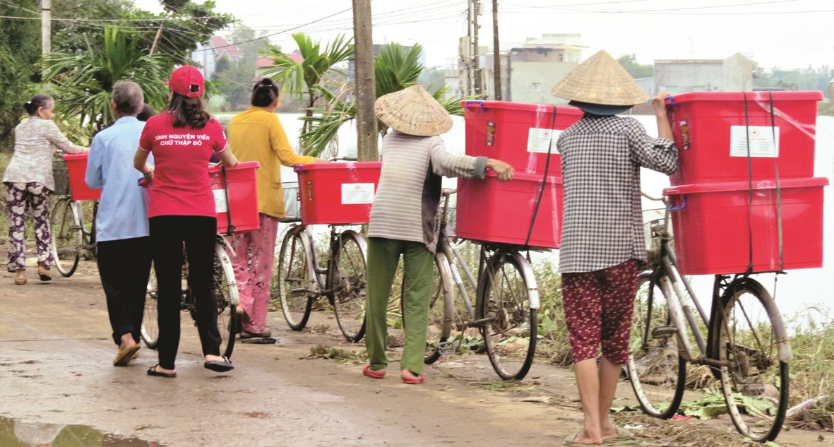 Người dân vùng lũ lụt nhận thùng hàng do Hội Chữ thập đỏ trao tặng. Ảnh: CTĐ