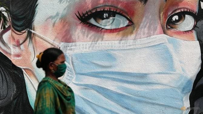 Người phụ nữ đi ngang qua bức vẽ cô gái đeo khẩu trang tại thành phố Mumbai, Ấn Độ giữa đại dịch vẫn diễn biến phức tạp tạ nước này. Ảnh: Reuters