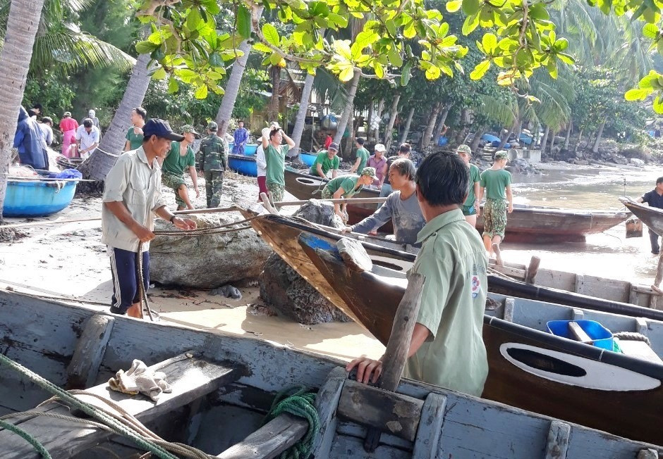 Lực lượng biên phòng giúp người dân đảo Cù Lao Chàm (xã Tân Hiệp) đưa những chiếc ghe lên bờ. Ảnh: BIÊN PHÒNG