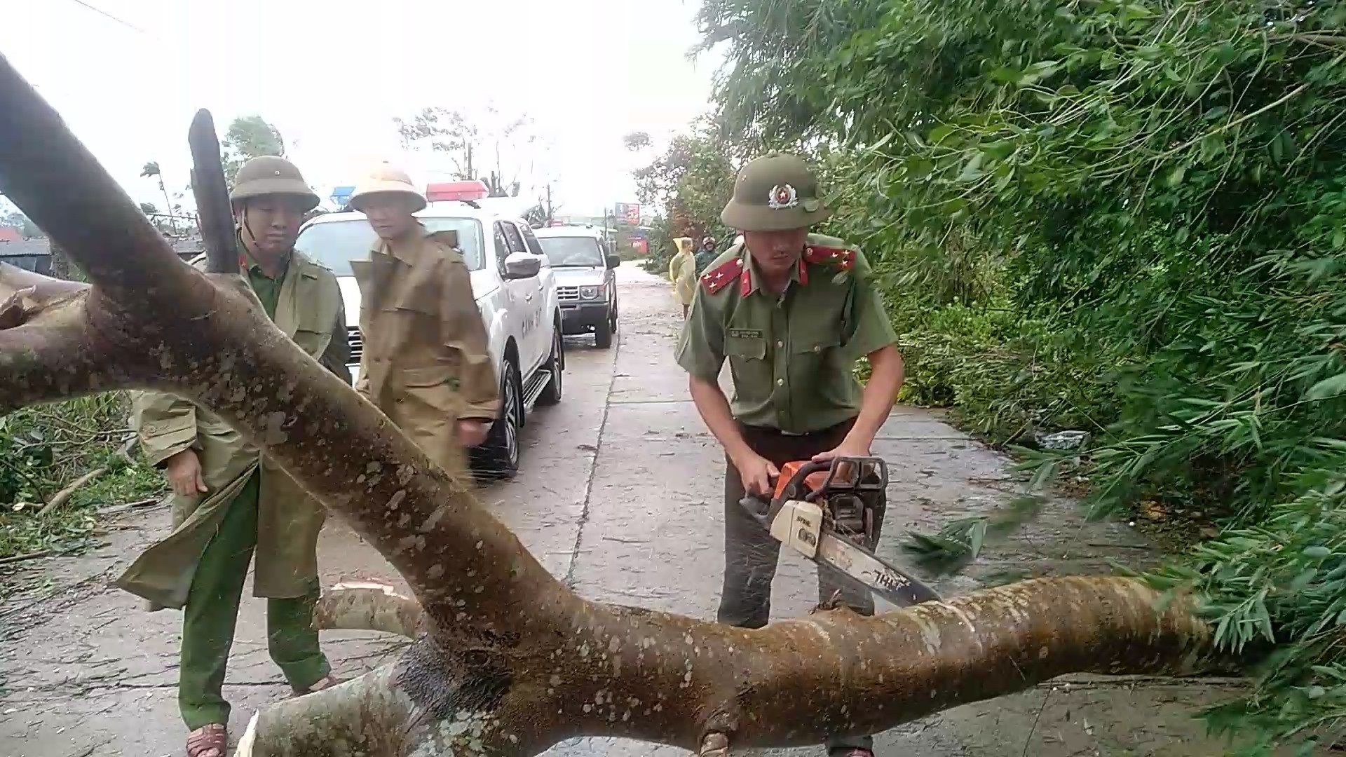 Lực lượng Công an Thăng Bình giúp người dân cưa cây, thông tuyến giao thông tại xã Bình Quý. Ảnh: M.TÂN