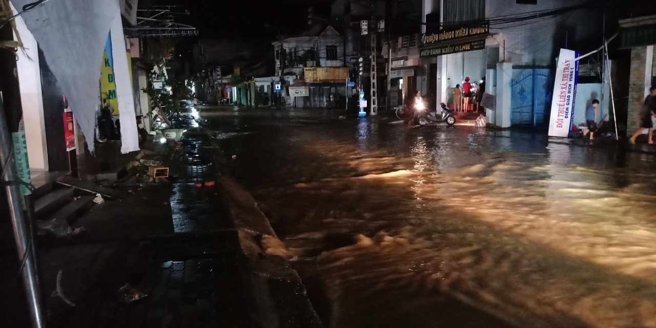 Nước lũ băng qua đường ở thị trấn Ái Nghĩa (Ảnh chụp lúc 8h30 phút tối 28.10). Ảnh: P. Đ.N