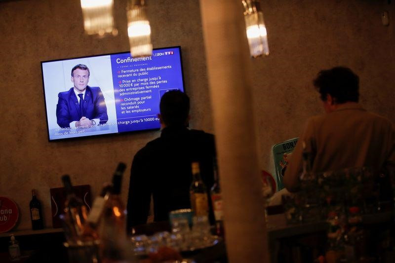 Người dân theo dõi thông báo mới nhất của Thủ tướng Pháp Macron liên quan đến Covid-19. Ảnh: Reuters