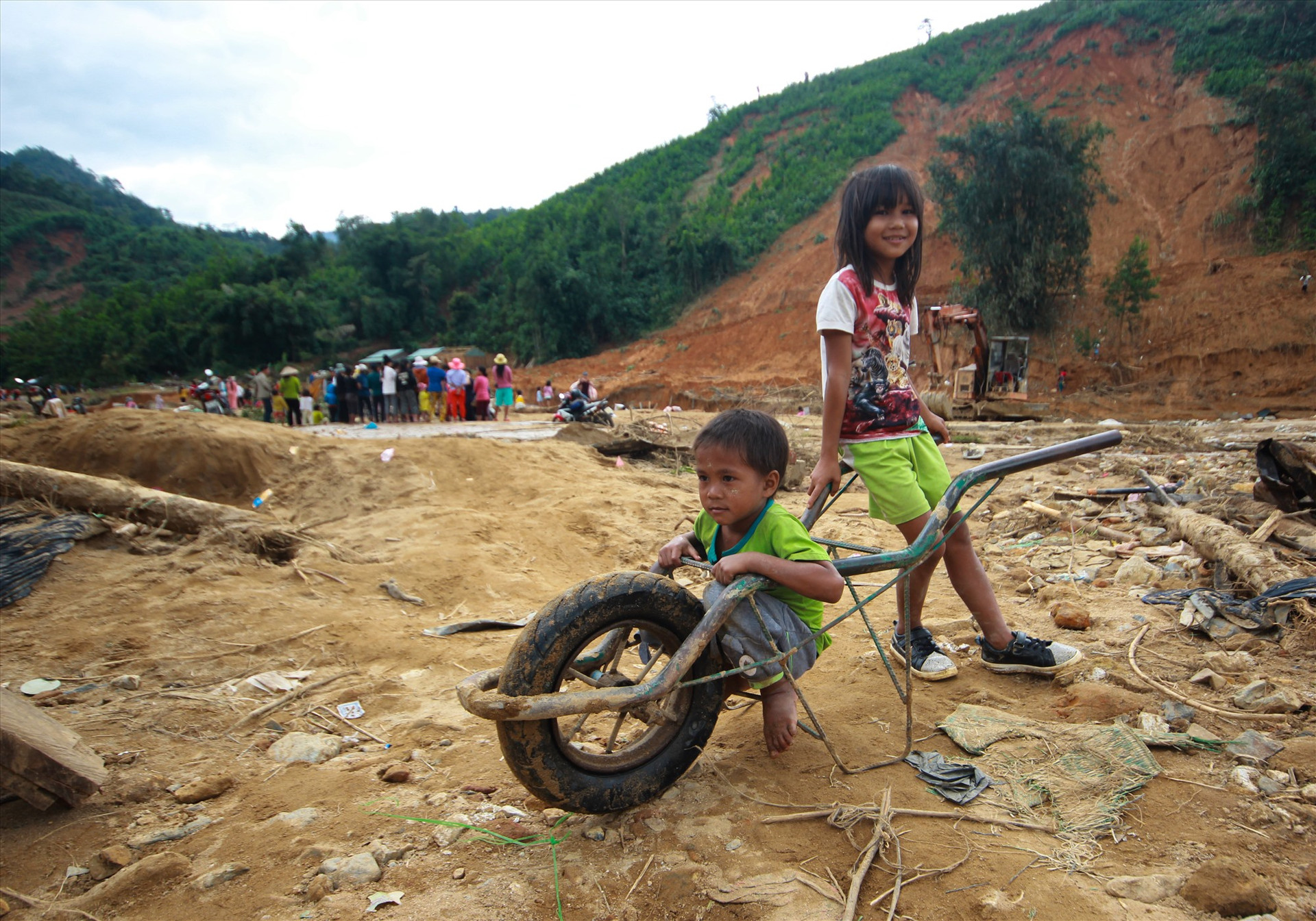 Hai em nhỏ thôn Trà Văn A lấy chiếc xe đẩy làm đồ chơi. Chiếc xe đẩy này bị hỏng sau khi được lôi ra từ đống bùn đất. Ảnh: T.C