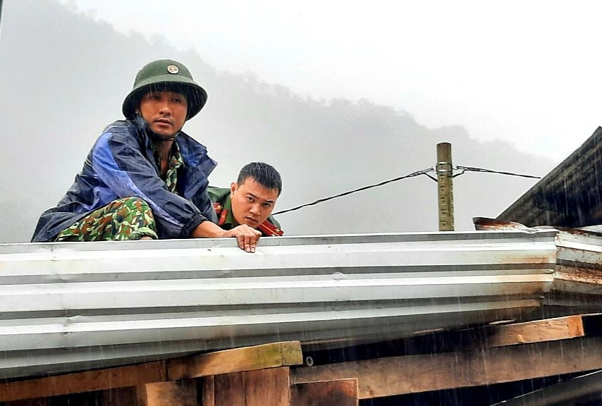 Trung úy Đoàn Thế Cẩm (bên trái) giúp người dân Phước Sơn lợp lại mái nhà sau bão. Ảnh: ALĂNG NGƯỚC