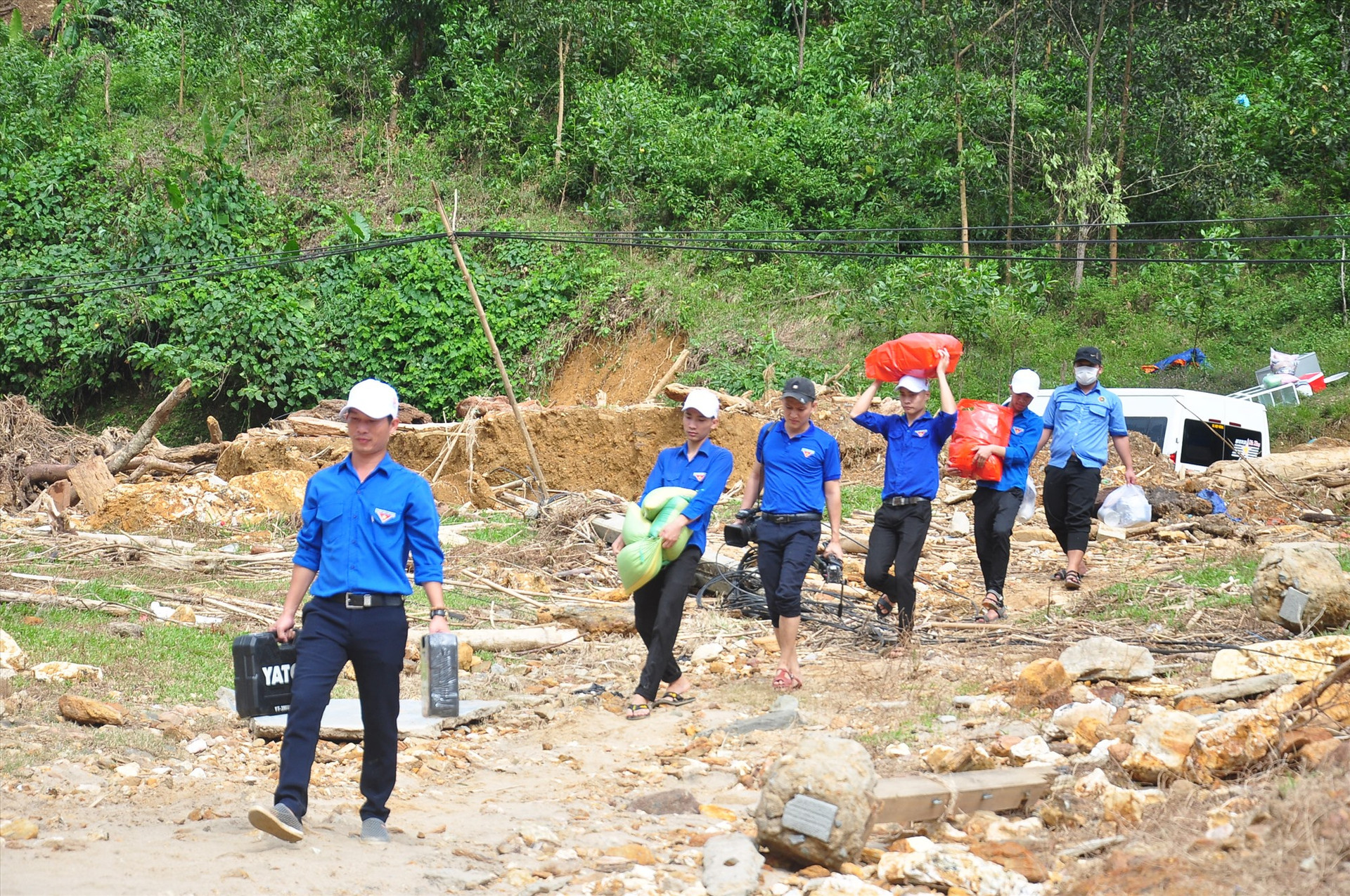Từ quốc lộ 40B, đoàn tình nguyện cùng nhau vận chuyển đồ đạc, hàng hóa xuống bên sông để qua làng Tắk Rối. Ảnh: VINH ANH