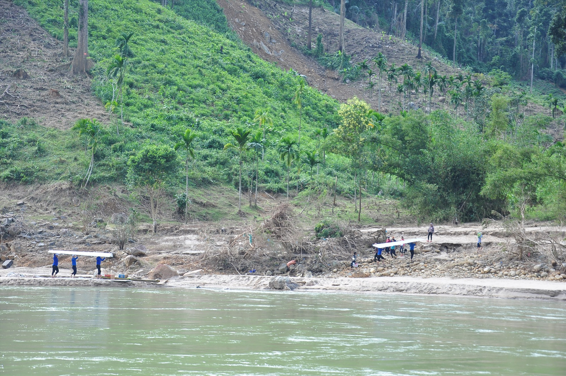 Sau vượt sông, thanh niên tình nguyện tiếp tục cõng tôn đi vào làng Tắk Rối. Ảnh: VINH ANH