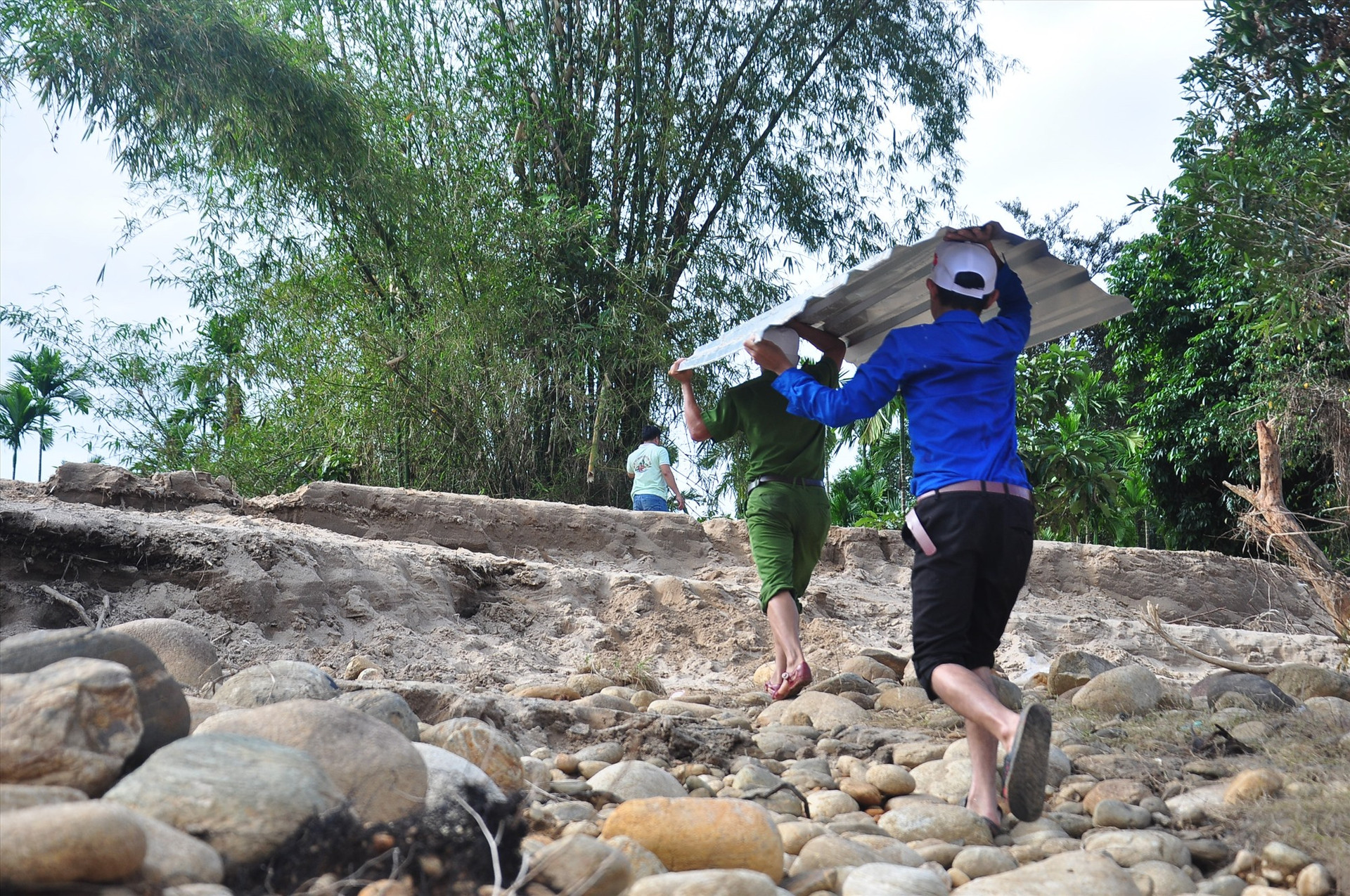 Thanh niên tình nguyện vận chuyển tôn từ bến sông vào làng Tắk Rối. Ảnh: VINH ANH