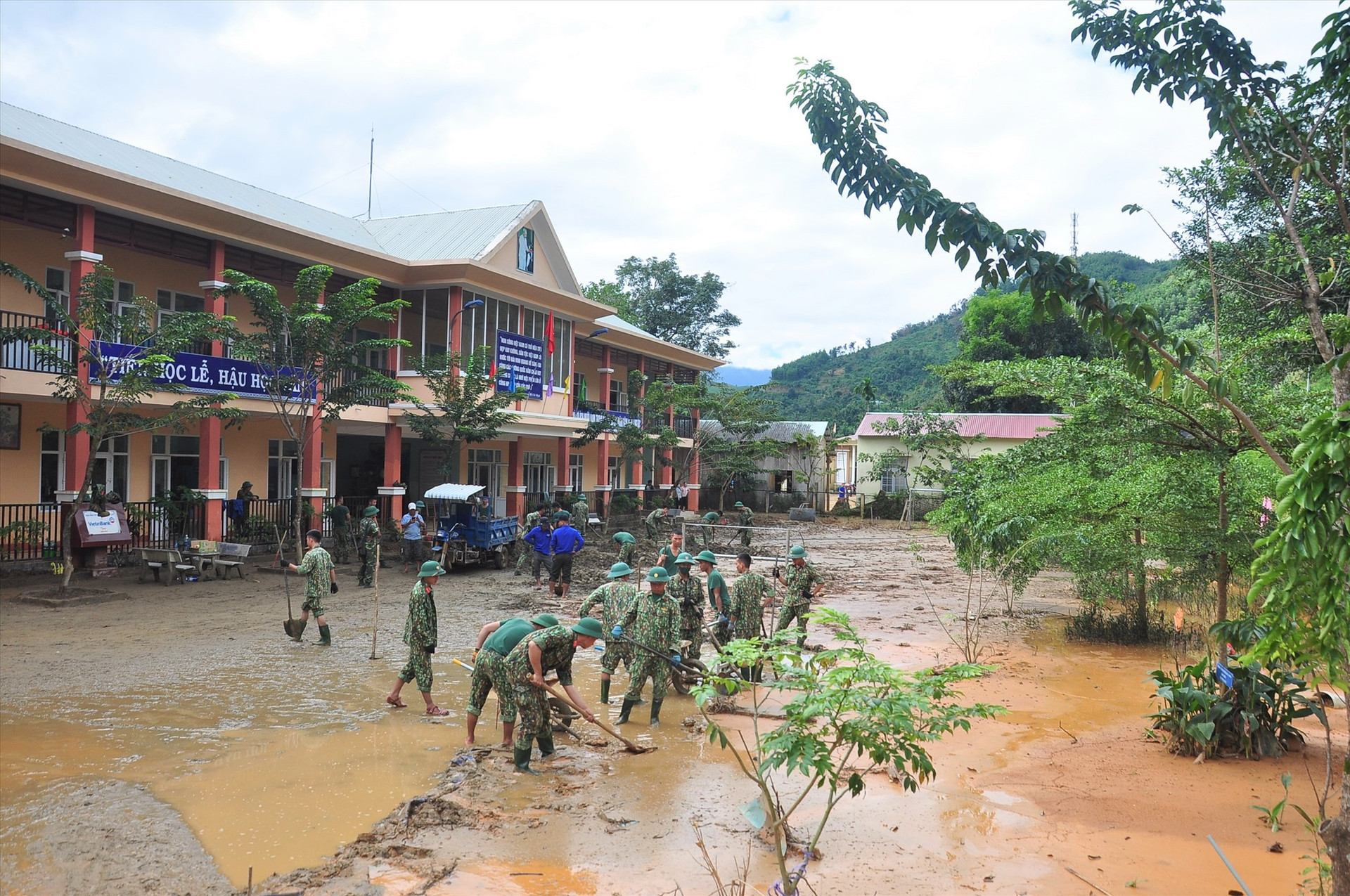 Bộ đội, thanh niên giúp Trường Phổ thông dân tộc bán trú tiểu học Trà Leng dọn dẹp bùn đất sau lũ. Ảnh: VINH ANH