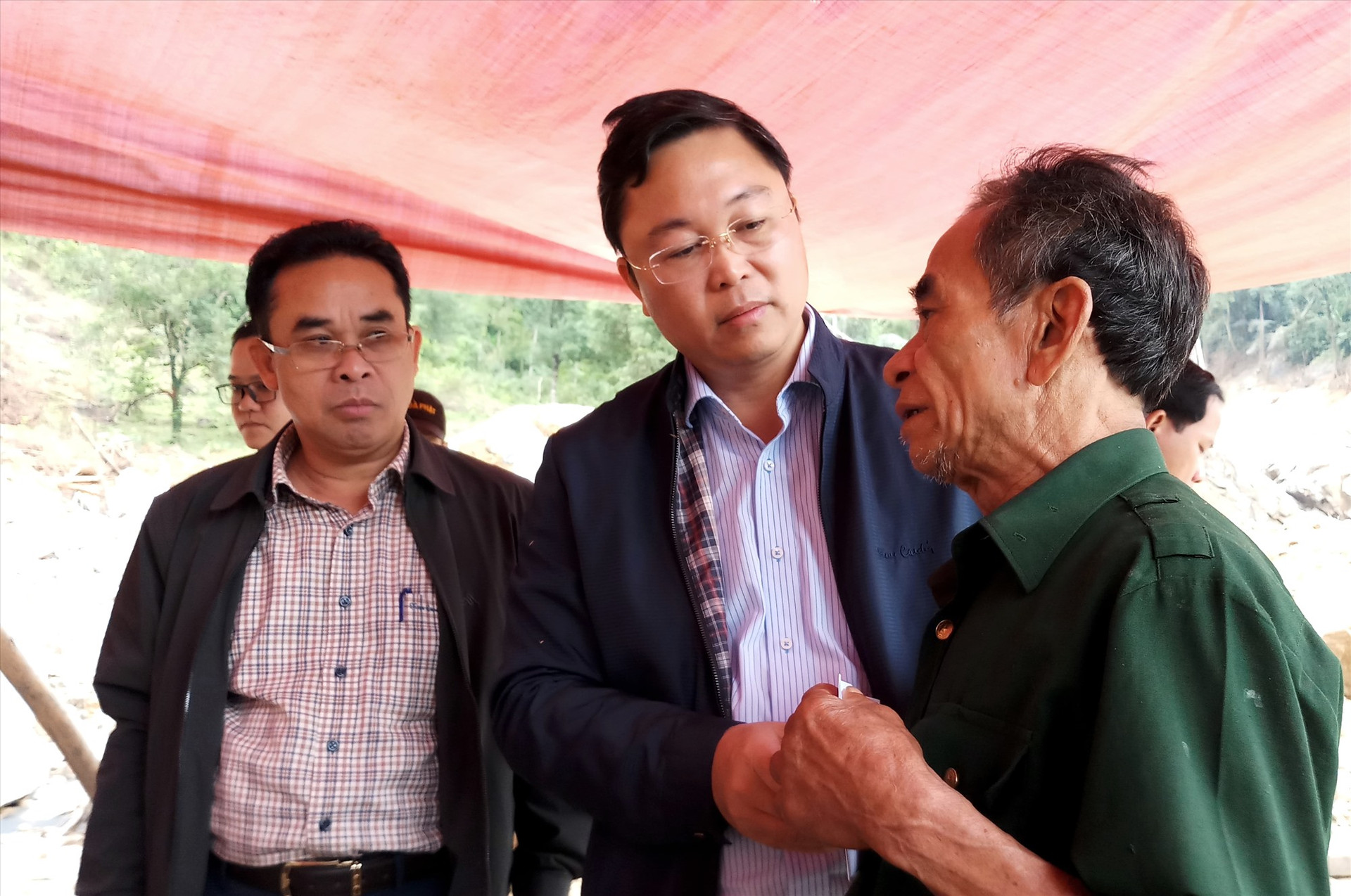 Chủ tịch UBND tỉnh động viên già làng Hồ Văn Đề, có đến 8 người thân chết và mất tích tại vụ lở đất ở Trà Leng vừa qua. Ảnh: A.N