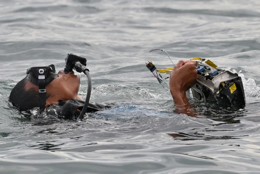 Thợ lặn Indonesia mang lên mặt nước một mảnh vỡ của máy bay gần đảo Lancang. Ảnh: AFP.