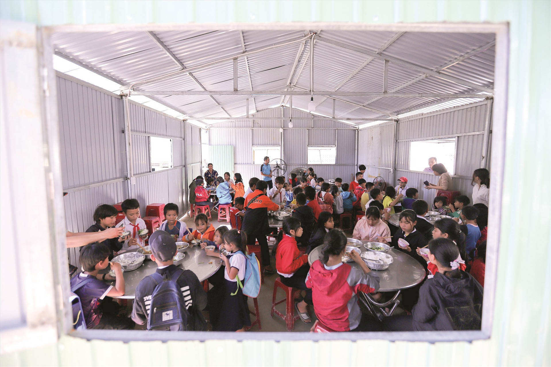 Bữa cơm của học sinh Trường Phổ thông dân tộc bán trú tiểu học và THCS Phước Kim trong căn nhà mái tôn vừa được dựng tạm, vì nhà ăn tập thể đã bị con suối phía sau trường phá sập một góc, nứt toác tường và nền.