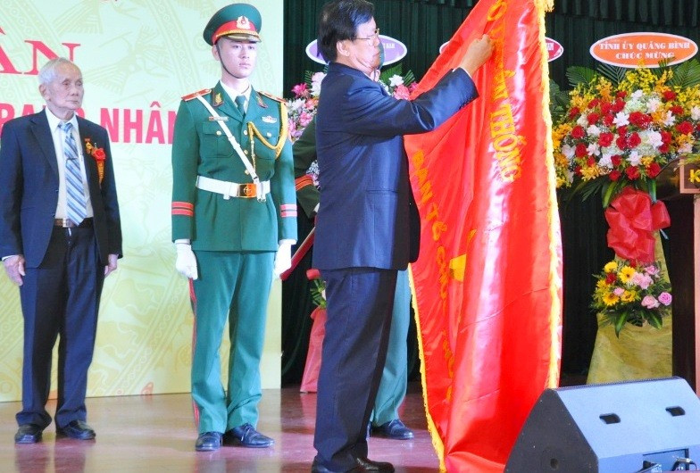 Thừa ủy nhiệm của Chủ tịch nước, đồng chí Hà Ban gắn danh hiệu cao quý lên lá cờ Truyền thống của Ban Tổ chức Khu ủy Khu 5