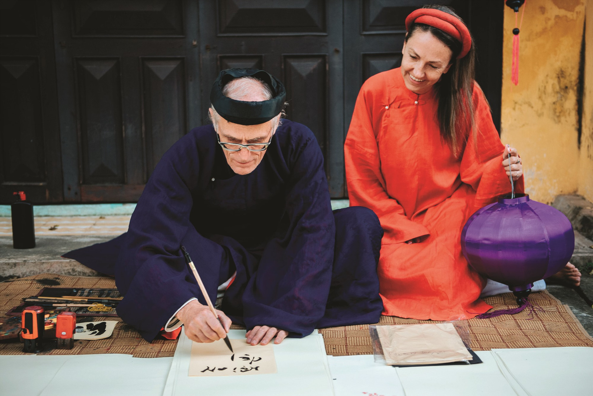 Lodo và vợ với áo dài khăn đóng ngồi trên phố viết thư pháp trong một sớm đầu năm dương lịch. Ảnh: HẢI HOÀNG