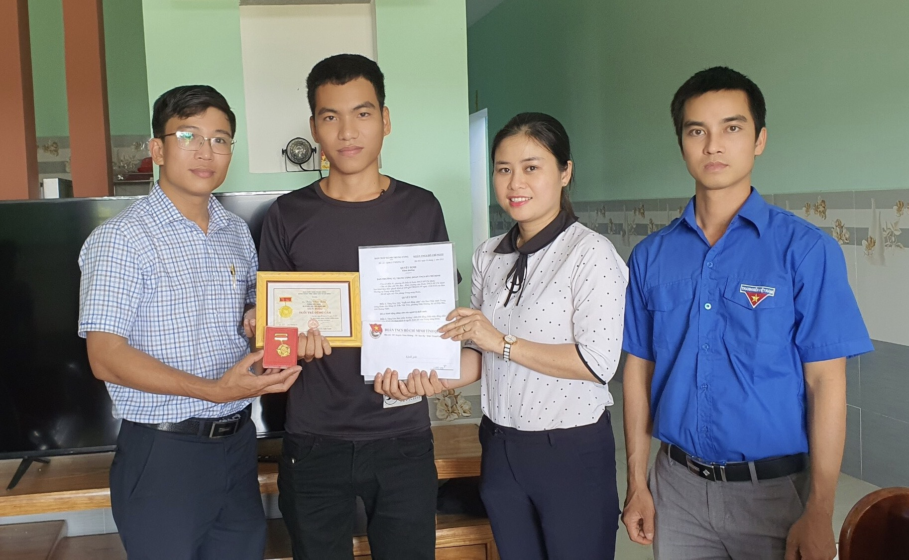 Anh Nguyễn Xuân Đức cùng cán bộ đoàn địa phương trao tặng Huy hiệu Tuổi trẻ dũng cảm cho anh Trần Văn Trong. Ảnh: T.ĐẠT