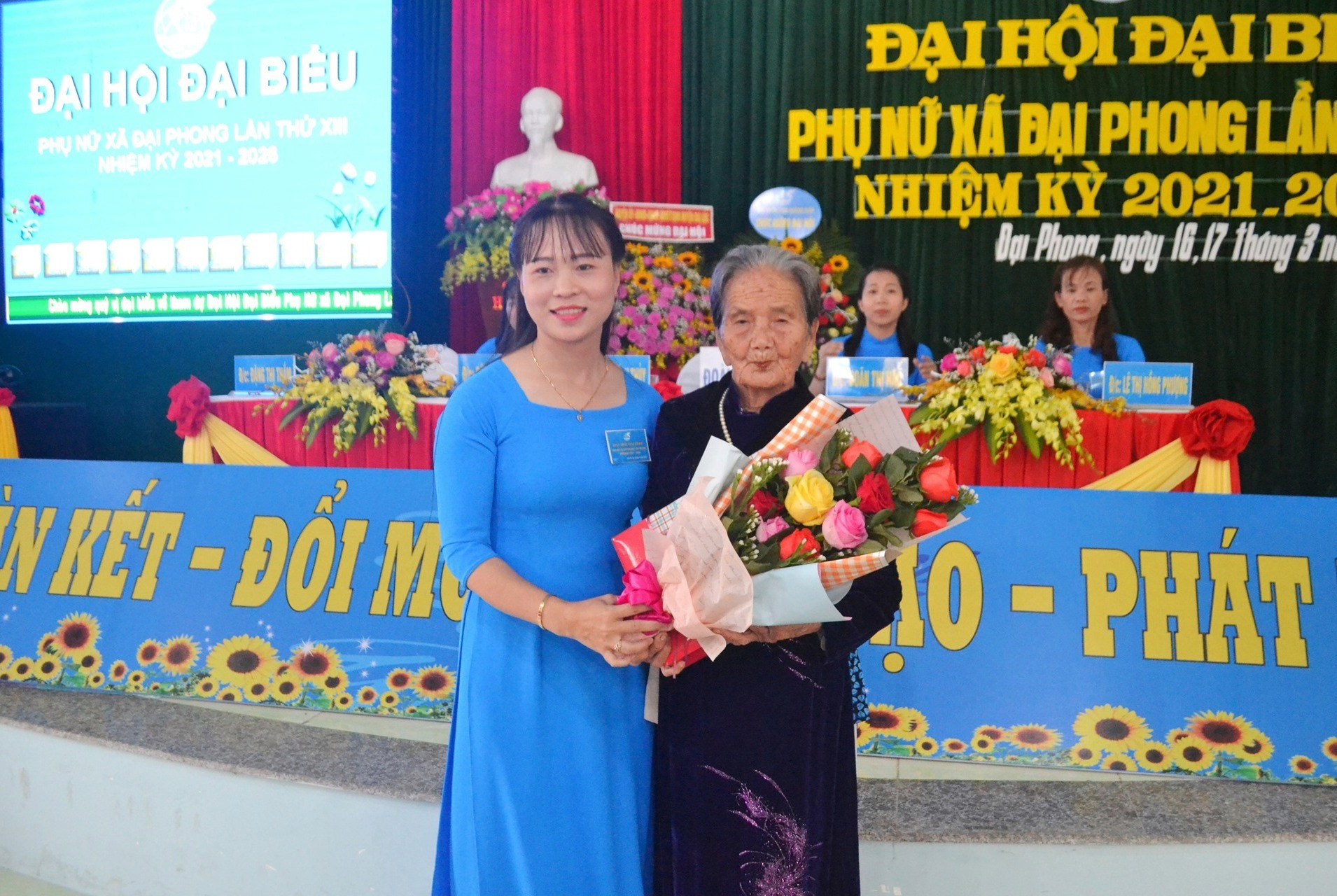 Chủ tịch Hội LHPN xã Đại Phong - bà Tào Thị Bích Thủy trao tặng quà và hoa cho Bà mẹ Việt Nam anh hùng. Ảnh: KK